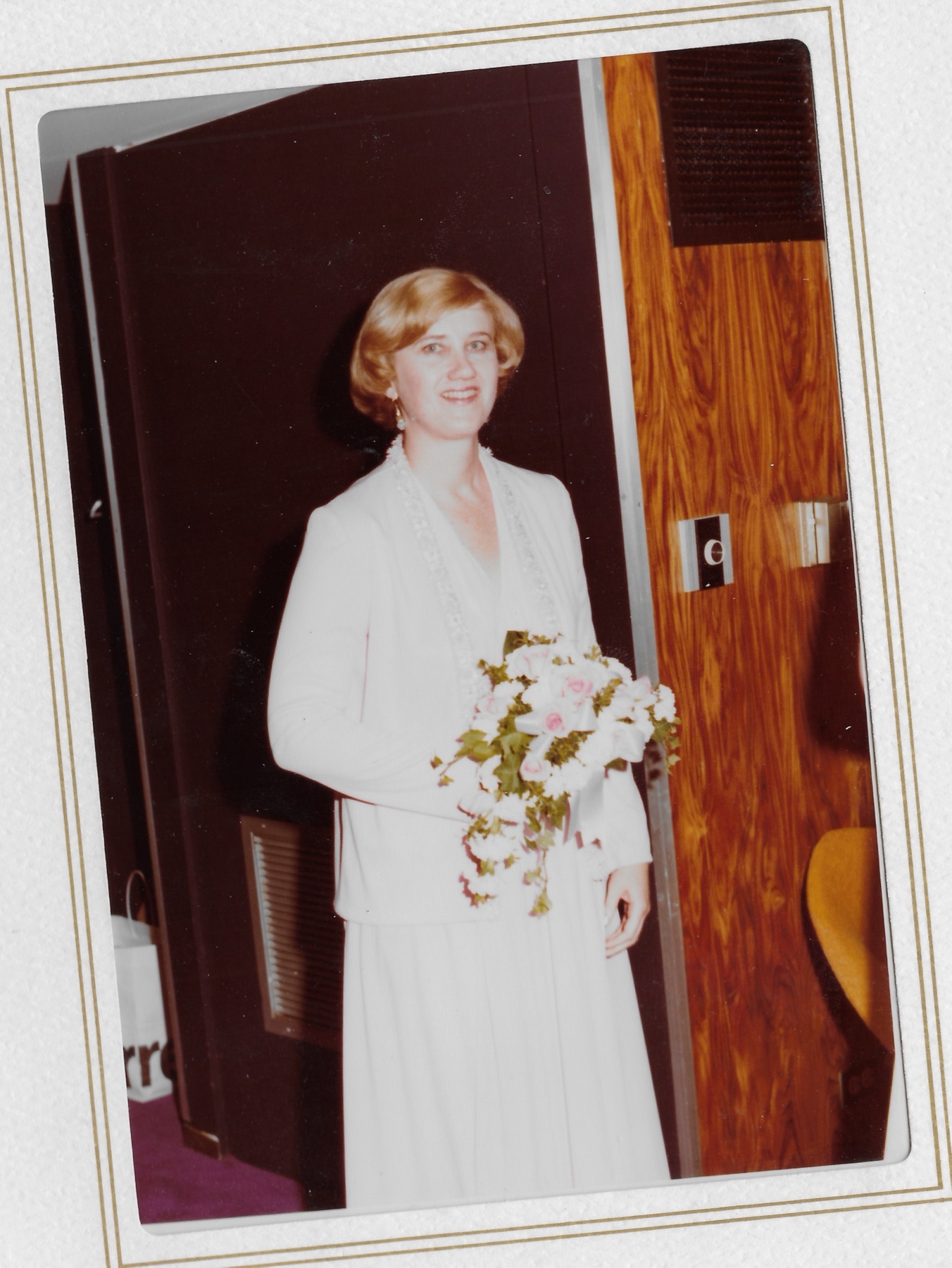 Mary Lee on her wedding day holding her bouquet in the doorway