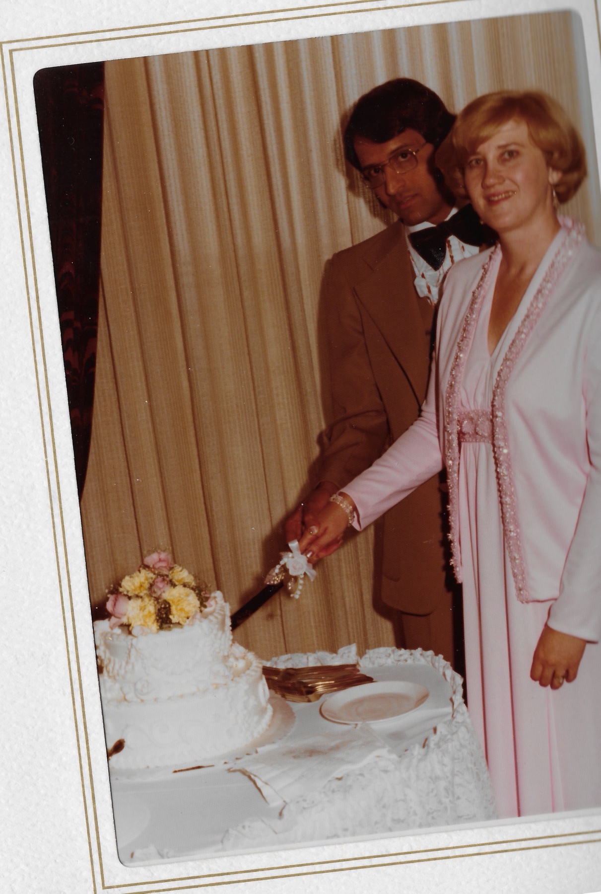 Cutting the wedding cake together, one hand over the other