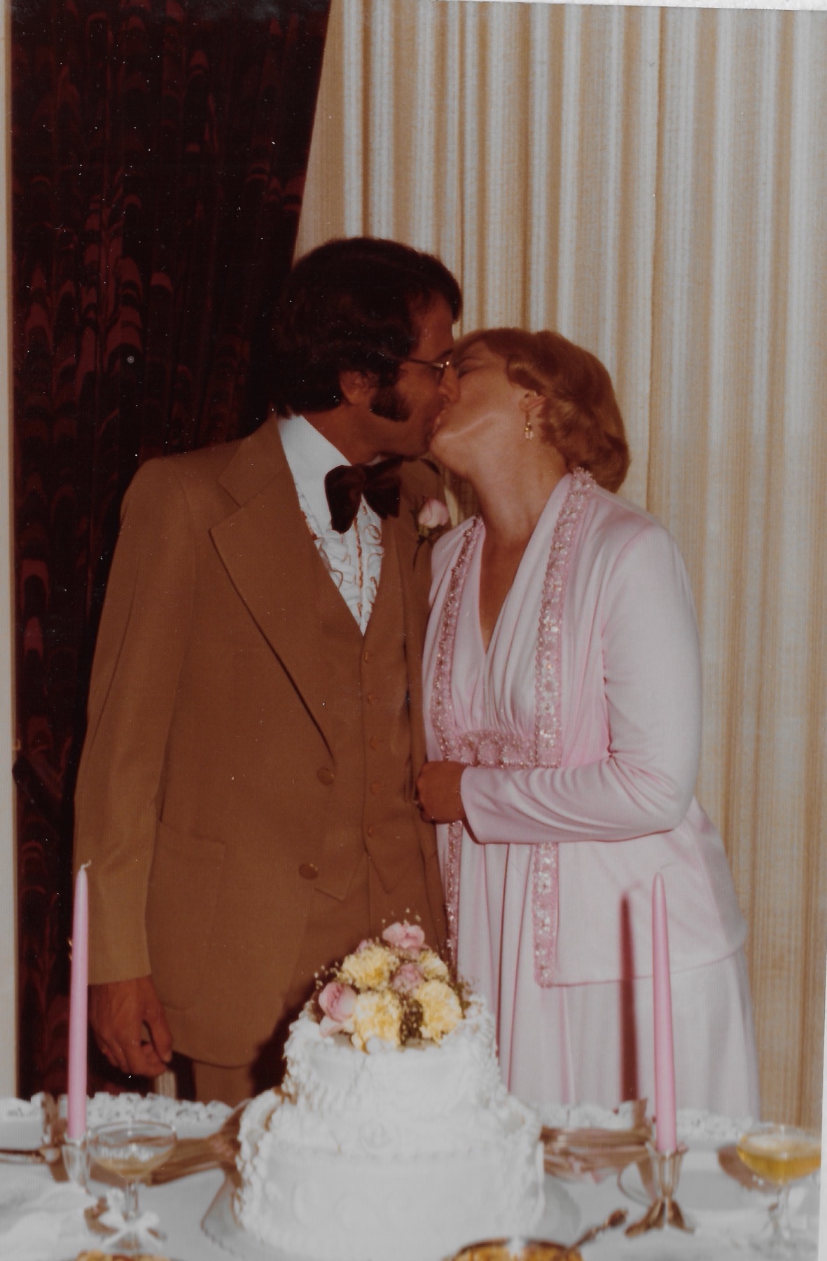 Mary Lee and Madhu kissing over the wedding cake