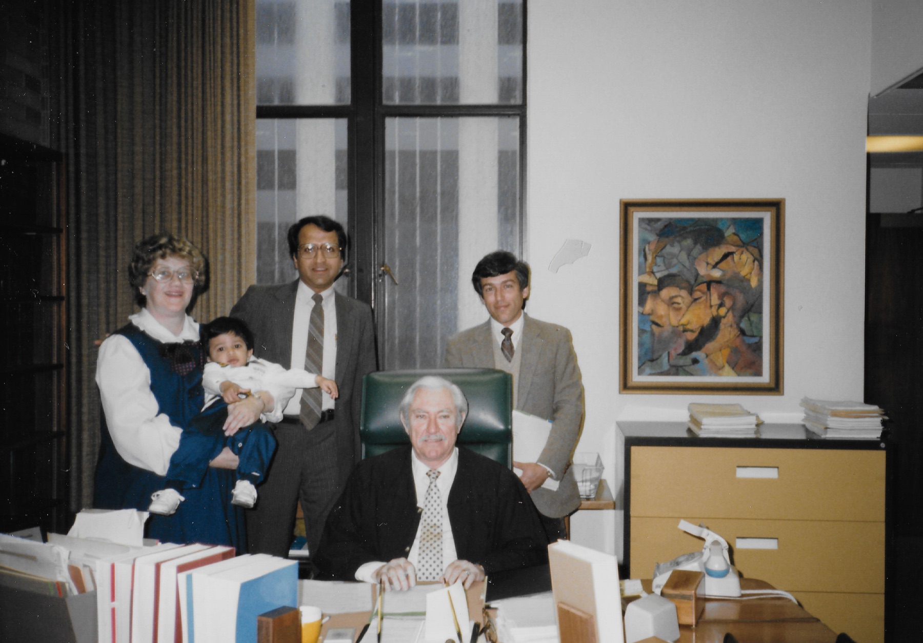 Mary Lee holding a baby beside Madhu in a judge&rsquo;s chambers on adoption day