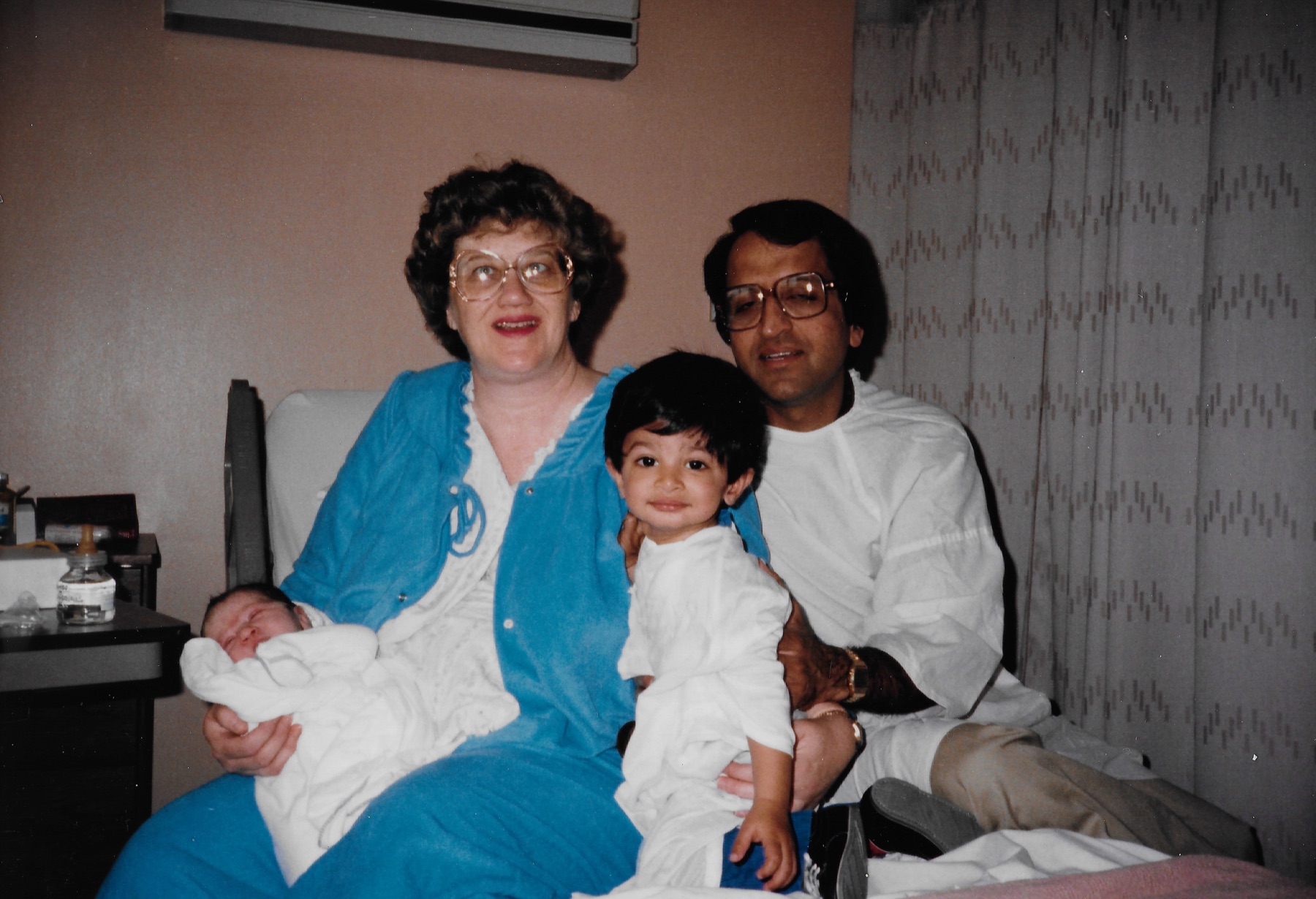 Mary Lee and Madhu at home with their children, holding a newborn